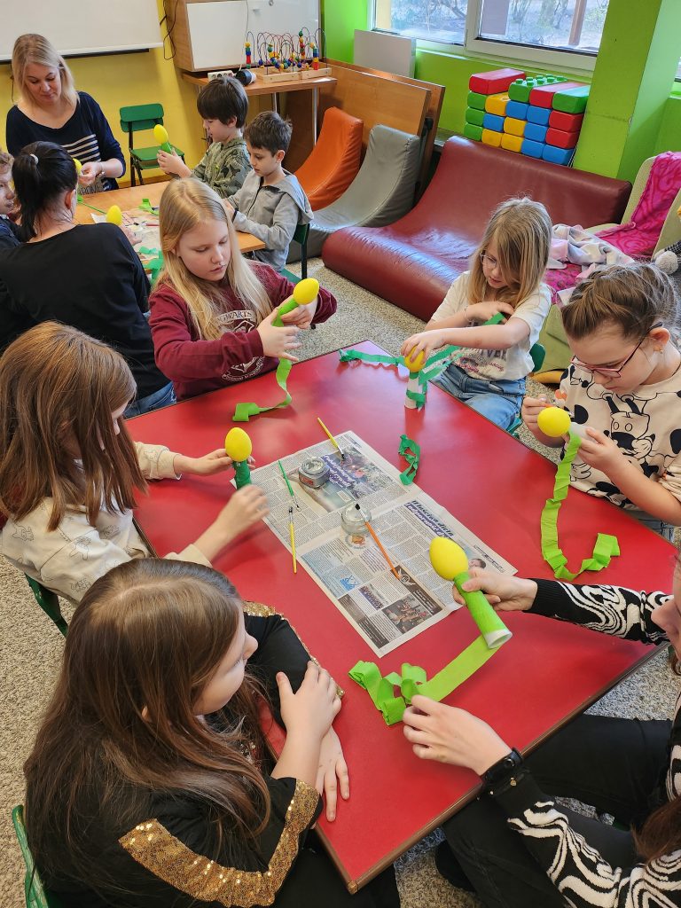 Zdjęcie przedstawia uczniów siedzących przy stole robiących prace plastyczną