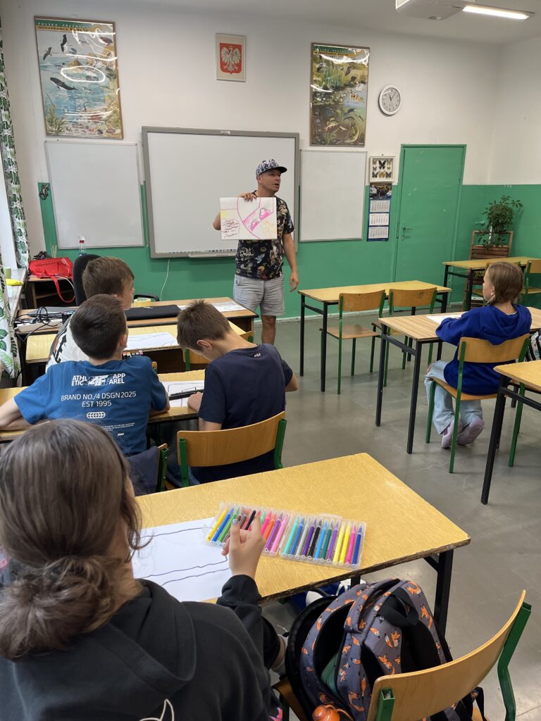 widzimy twórcę muralu prowadzącego warsztaty dla dzieci z naszej szkoły