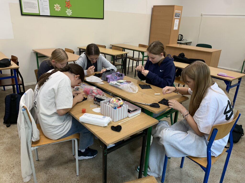 Uczennice siedzące przy ławkach robiące pracę