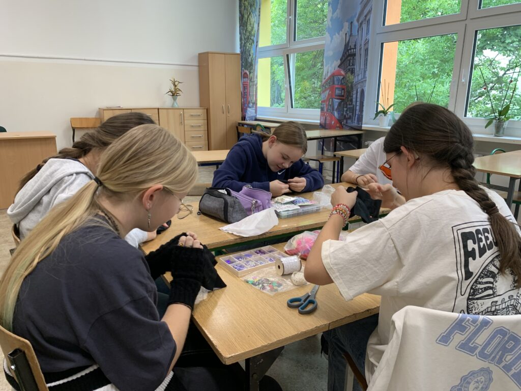 Uczennice siedzące przy ławkach robiące pracę