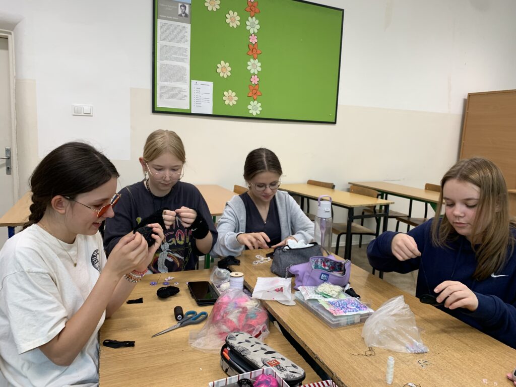 Uczennice siedzące przy ławkach robiące pracę