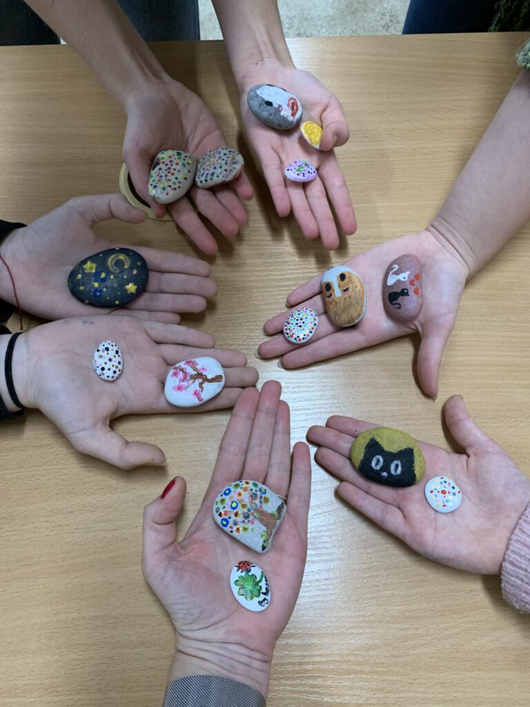 kolorowe pomalowane kamienie leżące na dłoniach uczniów 