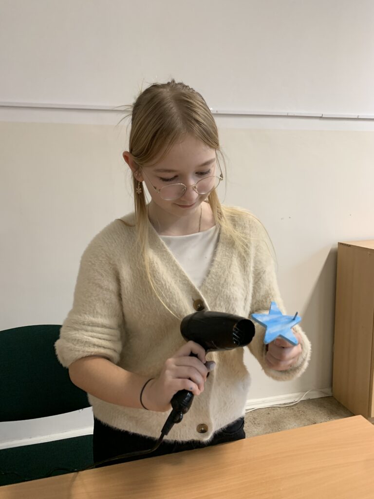 Uczennica susząca suszarką jej pracę