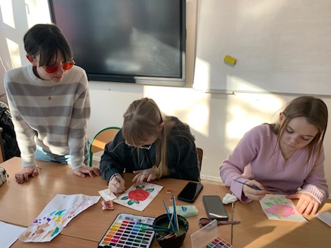 Dziewczyny z klasy 7 siedzące przy ławce malujące farbami