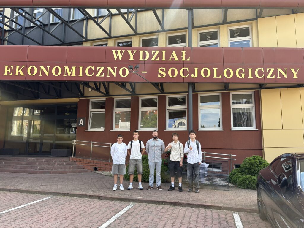 zdjęcie grupowe uczniów z panem Piotrem przed wydziałem